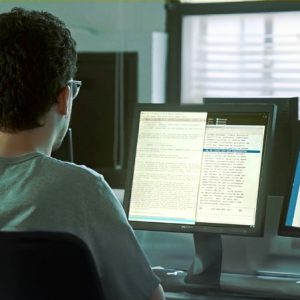 Imagem de uma pessoa de costas acessando o computador.